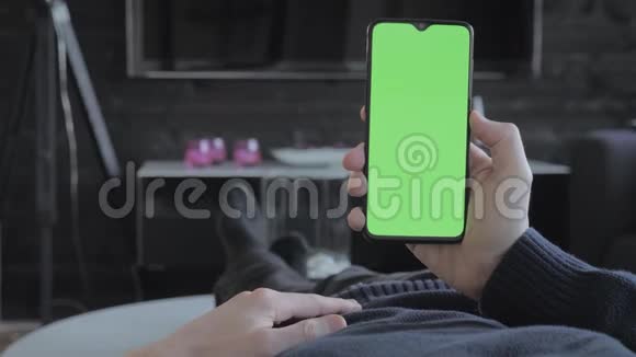绿色屏幕男人躺在沙发上看智能手机视频的预览图