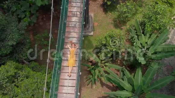 一名年轻女子的空中射击躺在丛林上空的吊桥上东南亚概念旅行视频的预览图