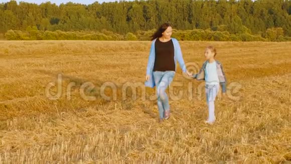 年轻的妈妈和女儿在秋收的时候走在麦田里视频的预览图