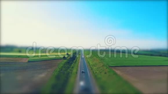 不同类型的汽车在穿过绿色草地和农业的空砾石路上行驶的空中模糊景象视频的预览图
