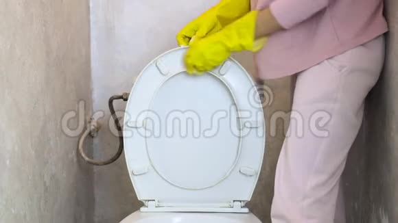 一个带黄色橡胶手套的女孩用海绵清洁马桶盖视频的预览图
