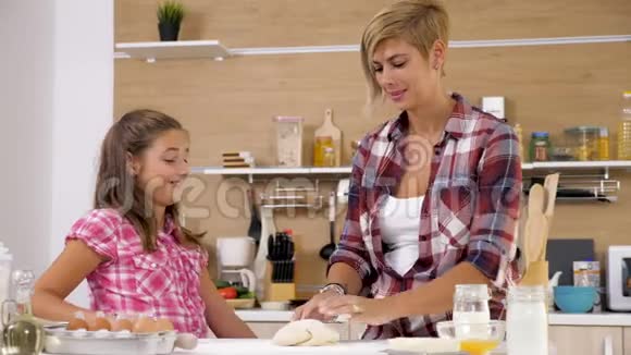 漂亮的妈妈在厨房里和她年轻的面团工玩乐视频的预览图