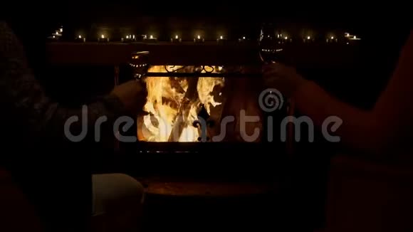 年轻夫妇在舒适的壁炉旁粘着酒杯和白酒视频的预览图