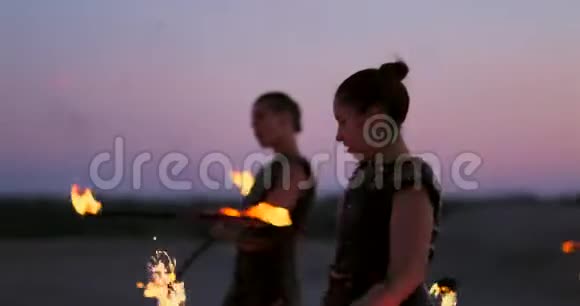 职业舞蹈家妇女在节日里用燃烧的闪闪发光的火把进行火秀和烟火表演视频的预览图