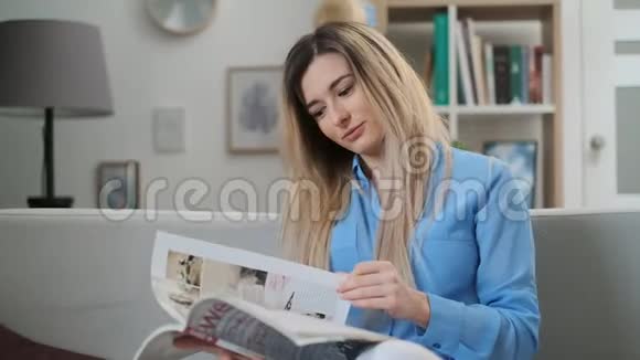 年轻女子在家阅读杂志的肖像坐在时尚杂志上翻页的迷人女孩视频的预览图