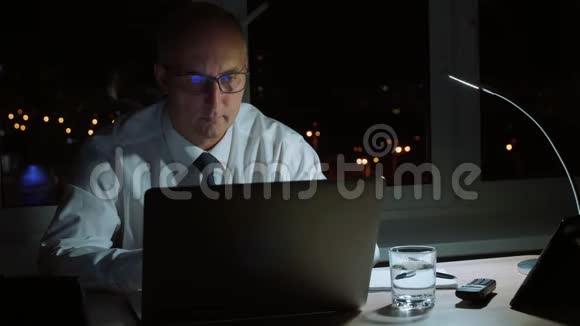 执行公司的商人们晚上用笔记本电脑和手机打电话视频的预览图