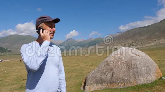 在绿色高地风景山地旅行时男子可拨打手机视频的预览图