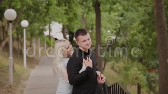 恋爱中的幸福夫妇站在树下的公园里视频的预览图