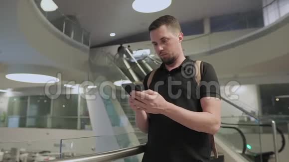 年轻人正在使用智能手机把它放在现代建筑的大厅里视频的预览图