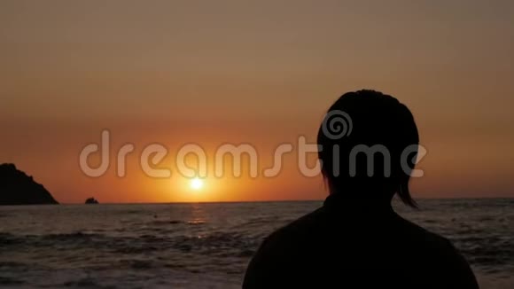 日出时坐在海边沉思的人的剪影视频的预览图