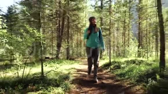 阳光明媚的一天年轻的女游客正在森林里散步正面观点视频的预览图