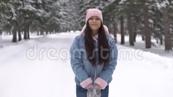 一个心情好的女孩把雪扔到她的头上在冬天的森林里旋转视频的预览图