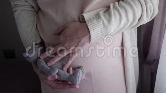 穿着桃色裙子抚摸熊玩具的孕妇视频的预览图