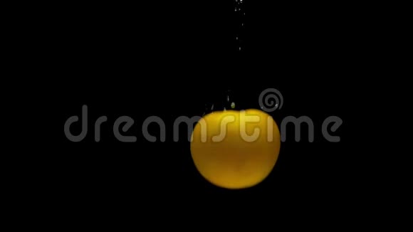 一个黄色的番茄落在黑色背景上的透明水中视频的预览图
