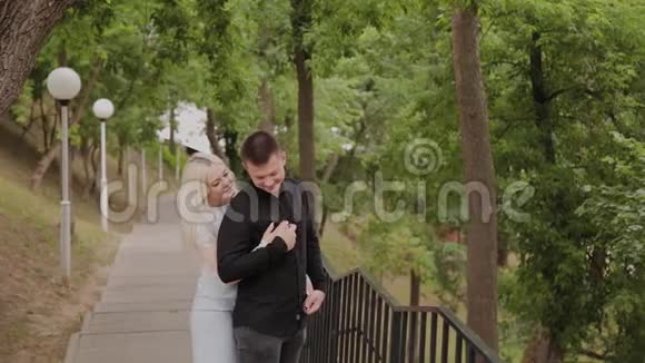 恋爱中的幸福夫妇站在树下的公园里视频的预览图