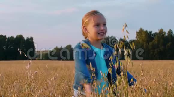 快乐的少年女孩在燕麦场跳舞少女漫步麦田视频的预览图