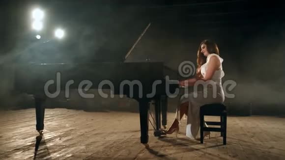 美丽的年轻女子穿着连衣裙在舞台上制作钢琴音乐4K段视频的预览图