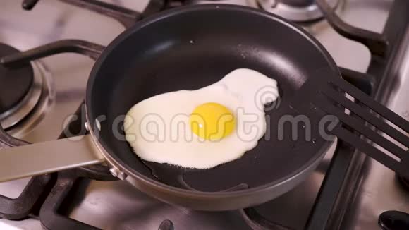 女人在家厨房炒鸡蛋在平底锅里加盐吃煤气灶视频的预览图
