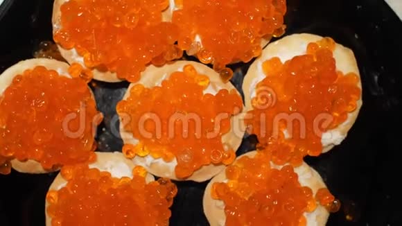 红鱼子酱是用勺子放在带有干酪的小馅饼上用红鱼子酱准备零食顶部视图视频的预览图