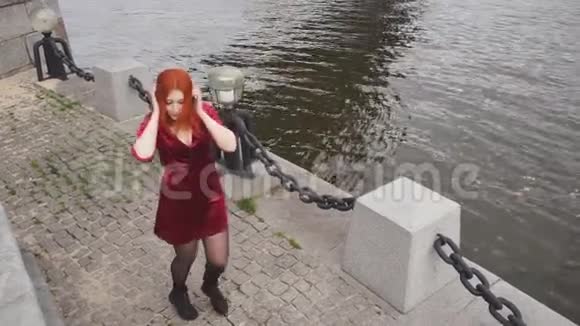 红发女孩手里拿着手机在河堤上跳舞视频的预览图