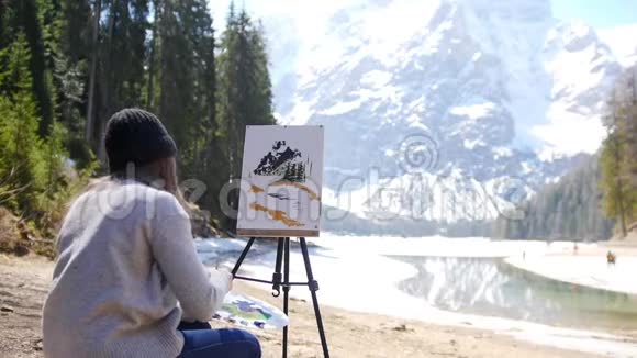 白云石一位年轻女子在画架上的画布上画山和森林视频的预览图