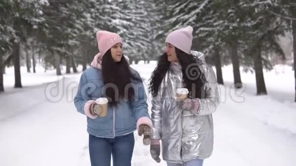 两个女朋友正在冬天的森林里散步手里拿着一杯咖啡心情很好视频的预览图