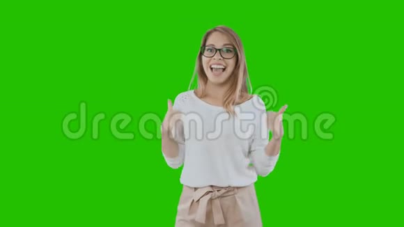 一位身穿节日服装戴着眼镜的年轻金发美女笑容满面双手撑着绿色的绿色衣服在课堂上展示视频的预览图
