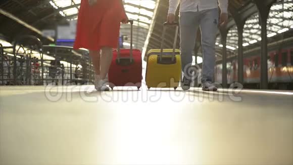 脚在站台上行走的乘客带着行李箱年轻夫妇沿着站台走到火车上视频的预览图