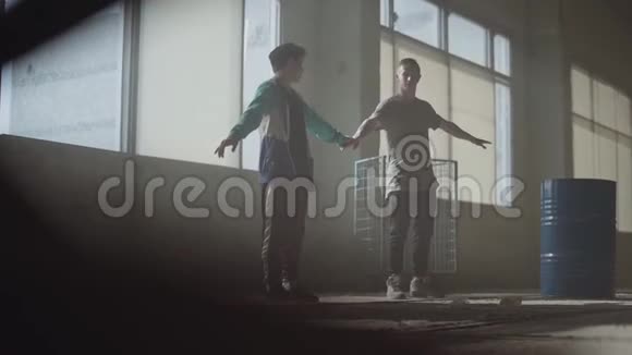 两个人在废弃建筑的黑暗和尘土飞扬的房间里跳舞青少年在跳舞的同时手持视频的预览图