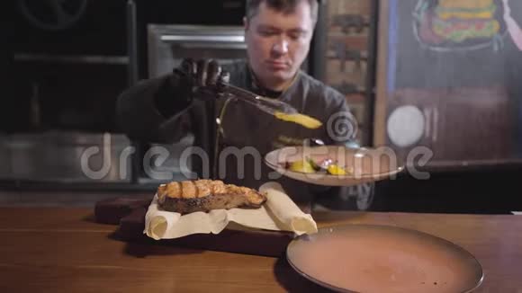 黑手套厨师端在木头上刚煮了美味多汁的鱼配烤甜椒辣椒和辣椒视频的预览图