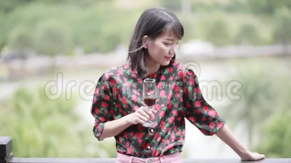 亚洲年轻女子端着酒杯脸上洋溢着幸福的笑容视频的预览图