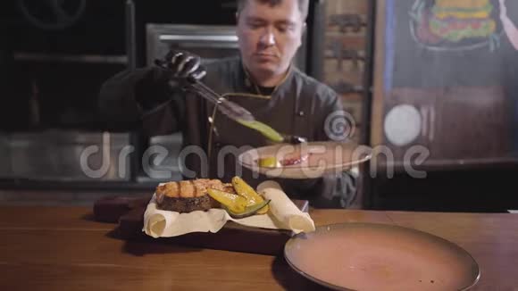 黑手套厨师端在木头上刚煮了美味多汁的鱼配烤甜椒辣椒和辣椒视频的预览图