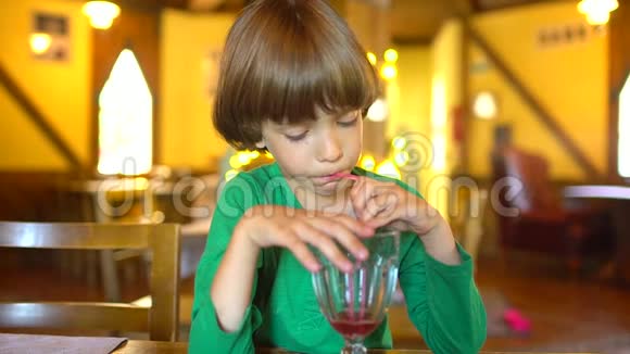 孩子喝果汁快乐的小可爱男孩通过吸管和微笑喝着浆果汁冰沙的肖像视频的预览图