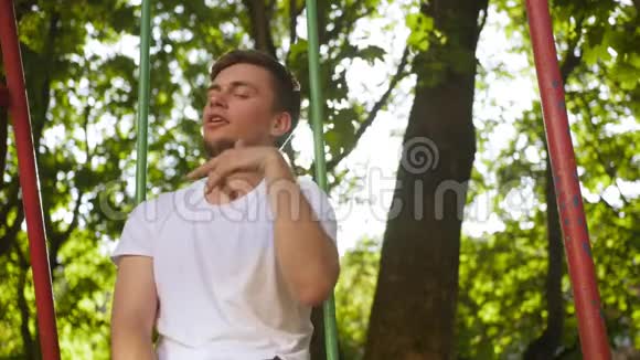 夏天一个穿着白色衬衫的人在树叶中的操场上嬉戏中弹视频的预览图