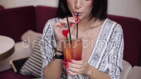 时尚女模特用手拿着杯子喝新鲜鸡尾酒的特写口视频的预览图