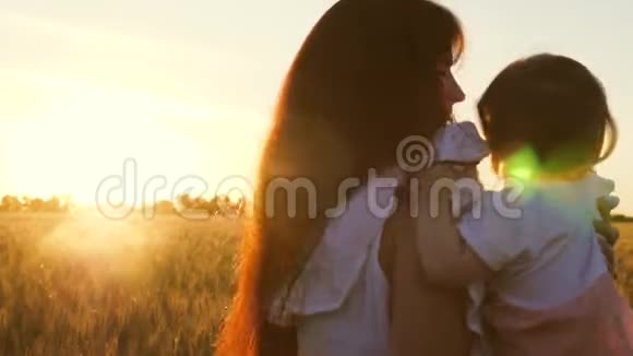 年轻的母亲带着她的小女儿在麦田里跳舞在美丽的夕阳下欢笑慢视频的预览图