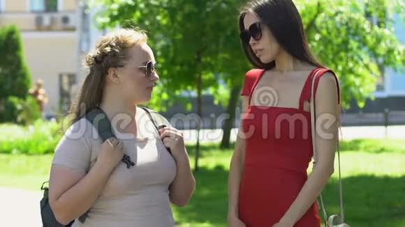穿红色裙子的苗条女人支持校园公园超重的女性朋友视频的预览图