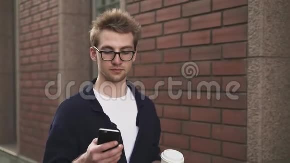 男人在街上散步时喝咖啡和上网视频的预览图