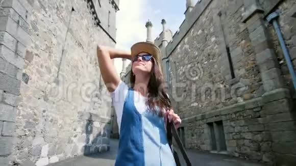 戴着太阳镜戴着帽子欣赏古老建筑的女背包客开心地微笑着视频的预览图