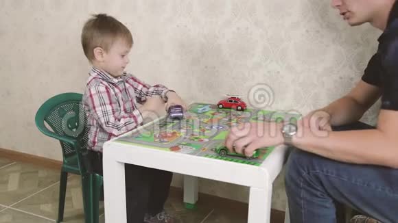 父亲和儿子在玩玩具车的同时也在微笑一起在家视频的预览图