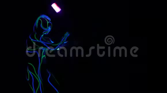 一个穿着发光服装的人站在黑暗和旋转的灯光下视频的预览图