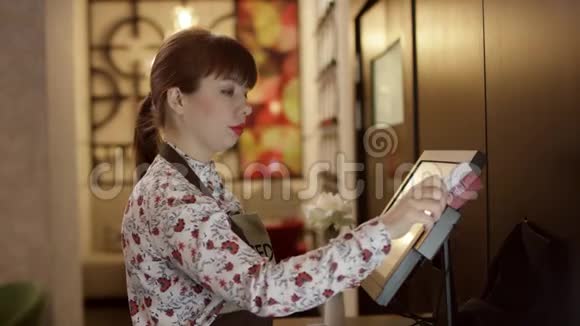 经理将触摸支付终端作为服务员在餐厅为顾客取桌账单的宽镜头视频的预览图