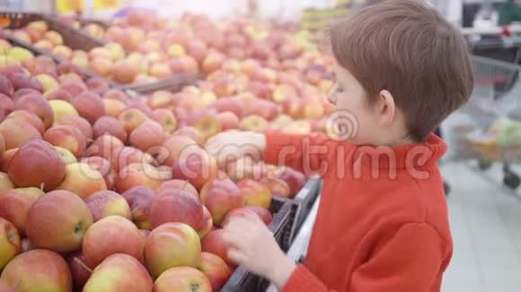 有趣的小男孩在超市的家庭购物中从盒子里摘苹果视频的预览图