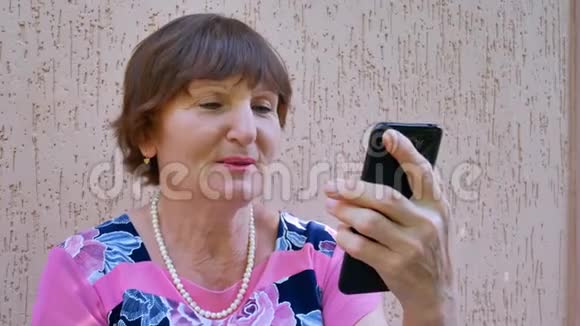 使用黑色智能手机进行在线视频聊天的老年妇女视频的预览图