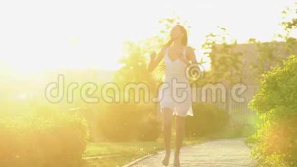 美丽的女孩在绿色公园的夏日里在夕阳下奔跑着玩自由健康幸福的理念快乐视频的预览图