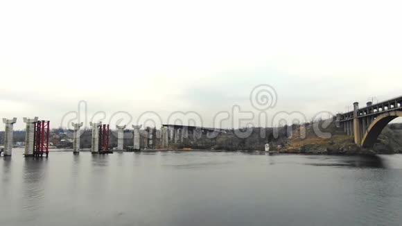 从河上的高角度看具有水中支撑的桥梁的施工现场视频的预览图