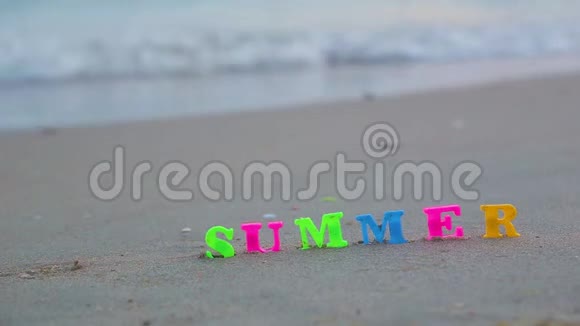 特写夏日用塑料彩色字母写在沙滩上迎着海浪视频的预览图