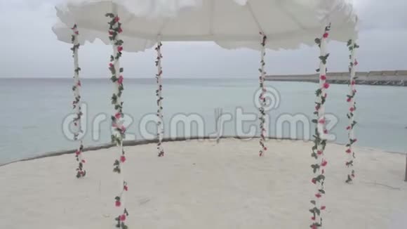在异国情调的度假胜地在海边的天空和水上装饰着鲜花的婚礼拱门视频的预览图