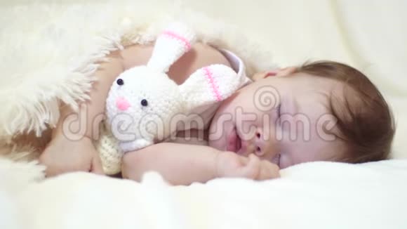 小宝宝睡在婴儿床上拥抱玩具兔子视频的预览图
