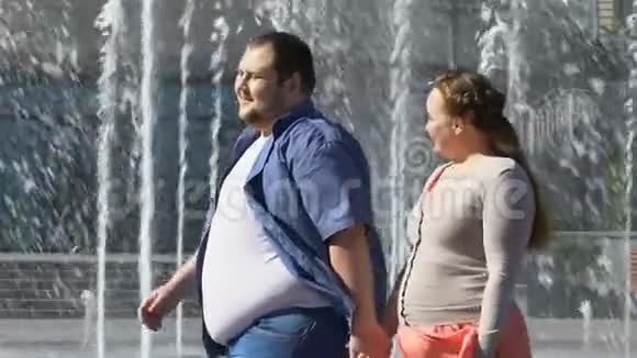 快乐的超重夫妇在喷泉旁散步牵手肥胖问题视频的预览图